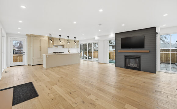 Open-concept kitchen and living room at 2212 Urwin Crescent in West Oakville with quartz counters, large island, engineered hardwood floors, and gas fireplace, presented by Roberto Ficzere